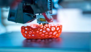 a 3d printer crafting a detailed, perforated red object with precision